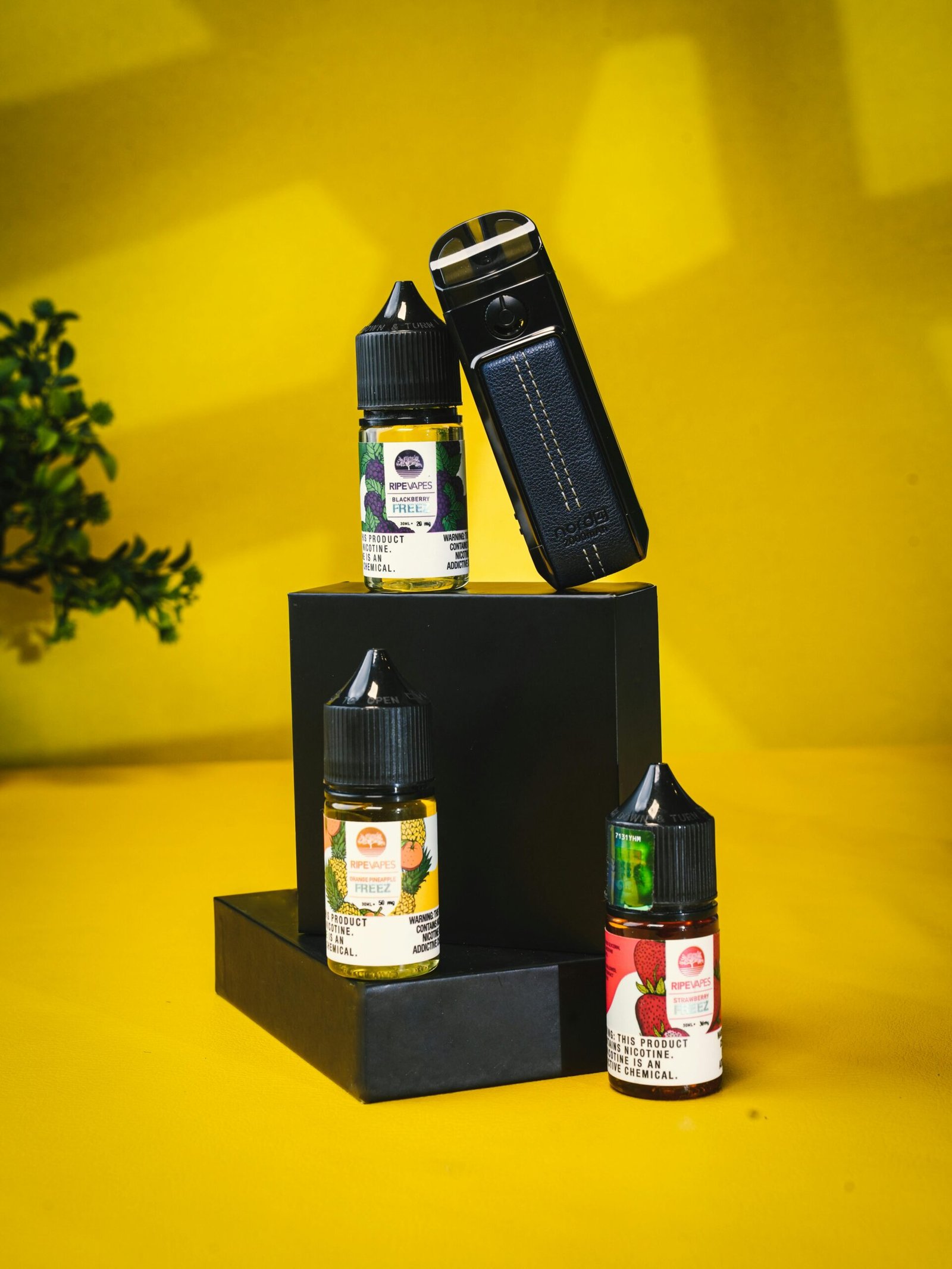 Vape device and e-liquid bottles displayed on a bright yellow background.